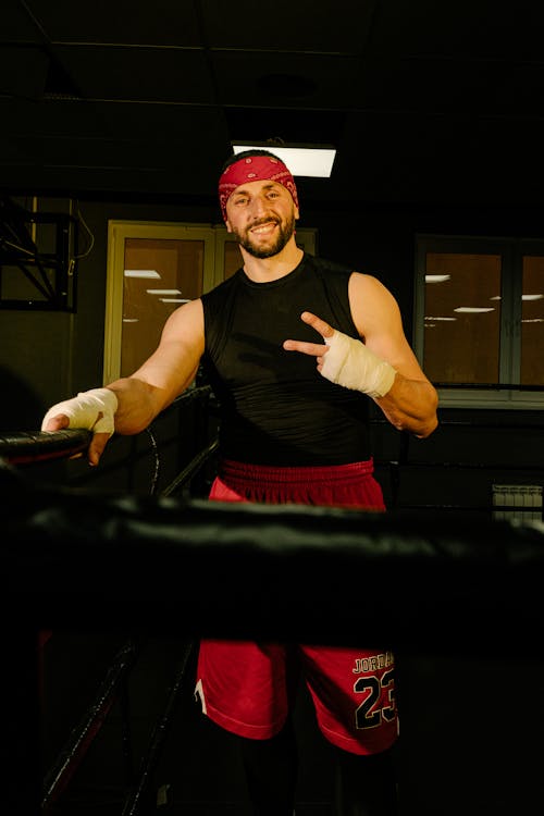 A Man in Black Tank Top and Red Shorts Smiling at the Camera