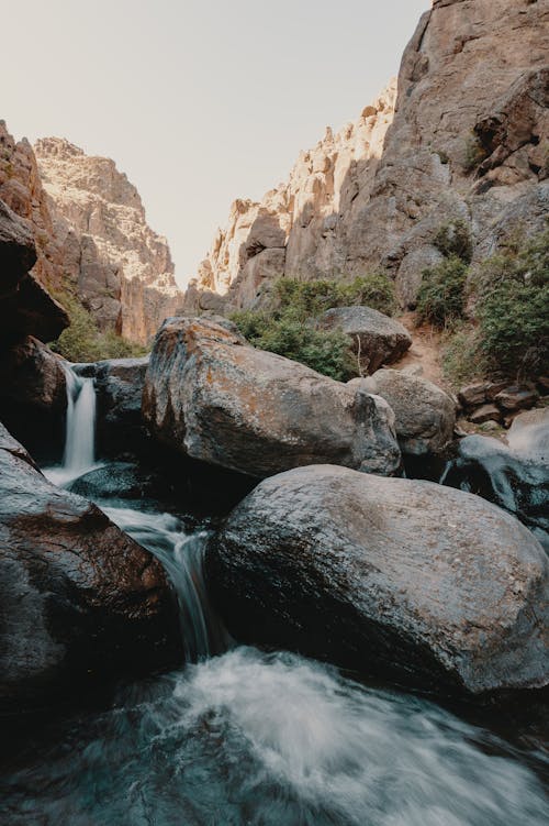 Mountainous terrain near stones with waterfall