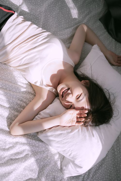 Free Asian woman smiling while lying comfortably in bed during morning. Stock Photo
