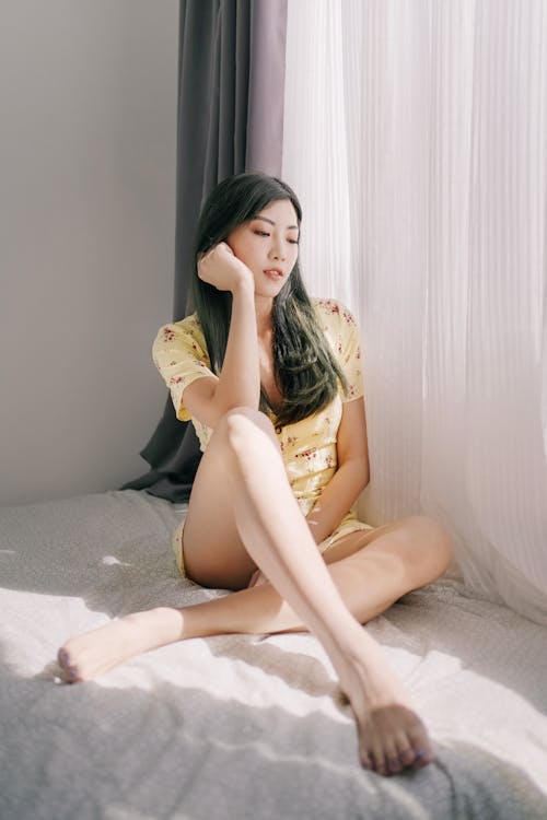 Female Wearing Floral Dress Sitting on Bed