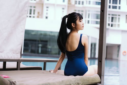 A Woman in Blue Swimsuit Sitting Beside the Swimming Pool