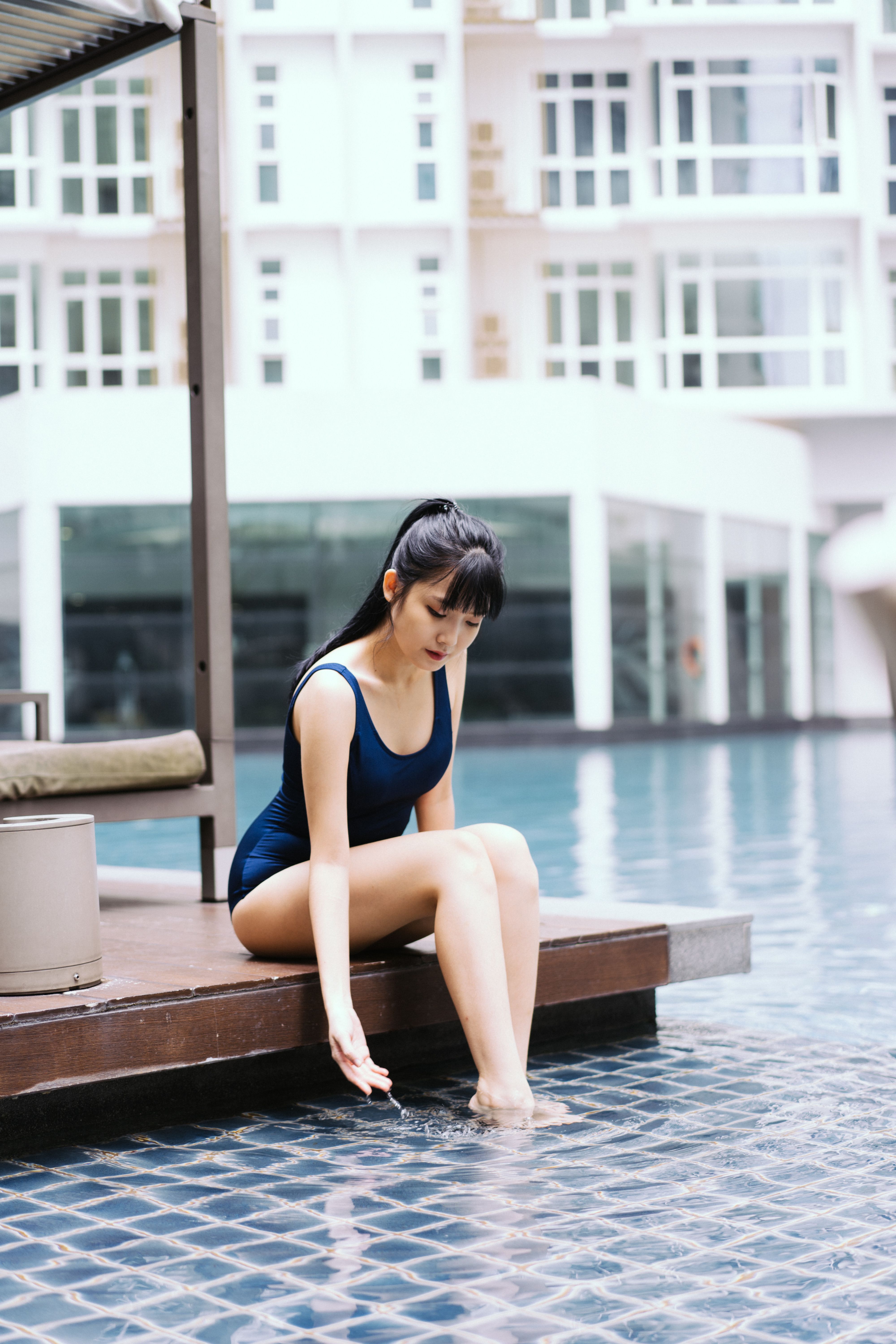 在度假村，一位年轻女子正静静触摸池水