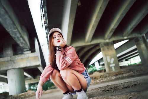 Free Stylish young woman in casual wear posing thoughtfully under an urban bridge. Stock Photo