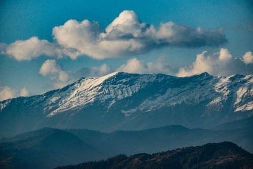 Free Breathtaking view of a snowcapped mountain range with clouds and blue skies, perfect for nature enthusiasts. Stock Photo