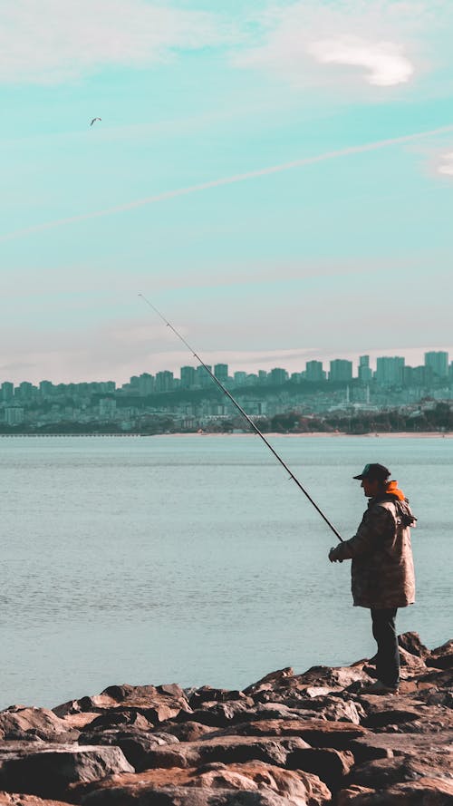 Unrecognizable male fishing on bay in city