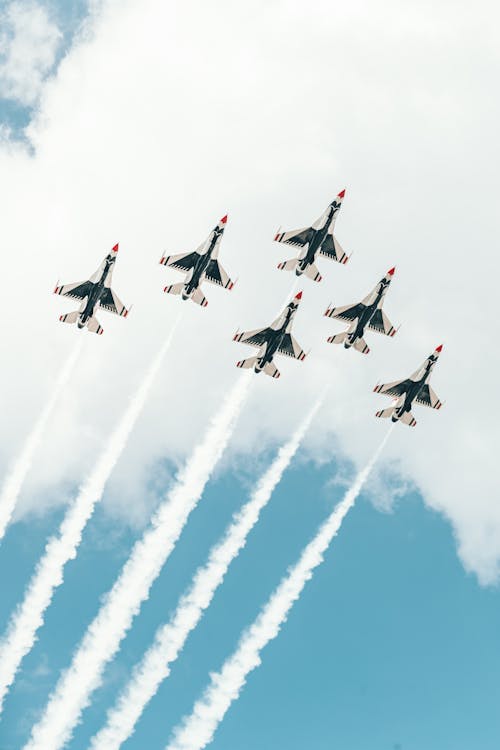 Free From below of small airplanes flying in sky symmetrically and leaving contrail in air Stock Photo