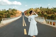 Relaxed woman in dress standing on road