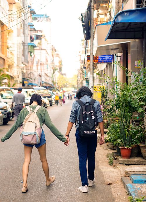 Free Back view of full body anonymous couple holding hands and walking along city street Stock Photo