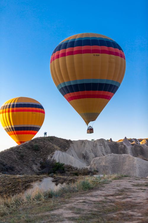 Free Vibrant hot air balloons soar over the unique rock formations of Cappadocia, Turkey, against a clear blue sky. Stock Photo
