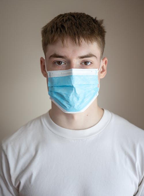 Free Calm young male in casual shirt and medical face mask against gray background Stock Photo