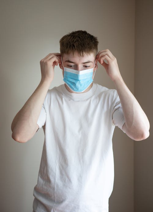 Young man putting on medical face mask