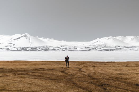 Lonely trekker in a vast snowy mountainous plain under clear skies in Georgia.