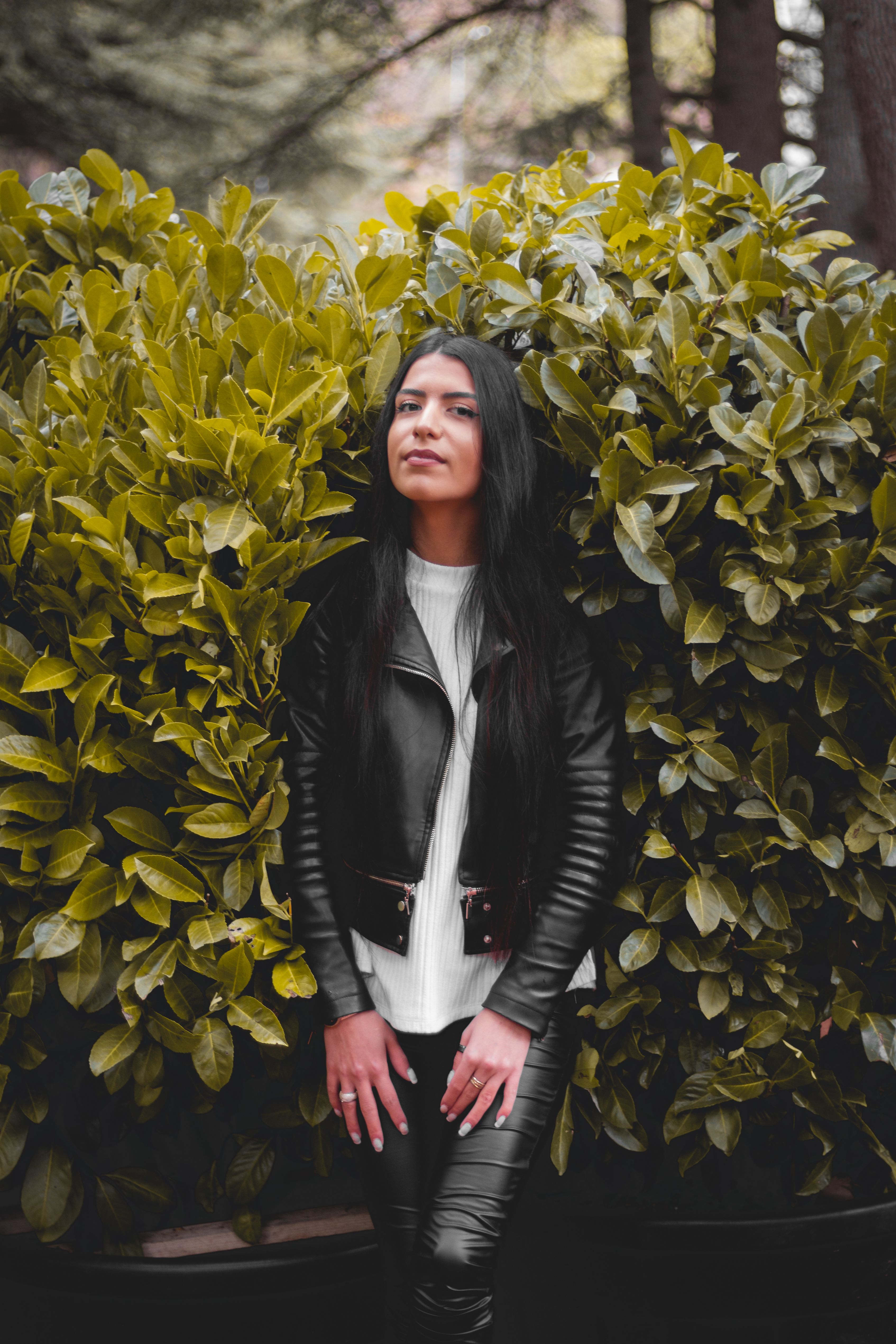 A Woman in Black Leather Jacket and Pants Standing on a White Surface ...