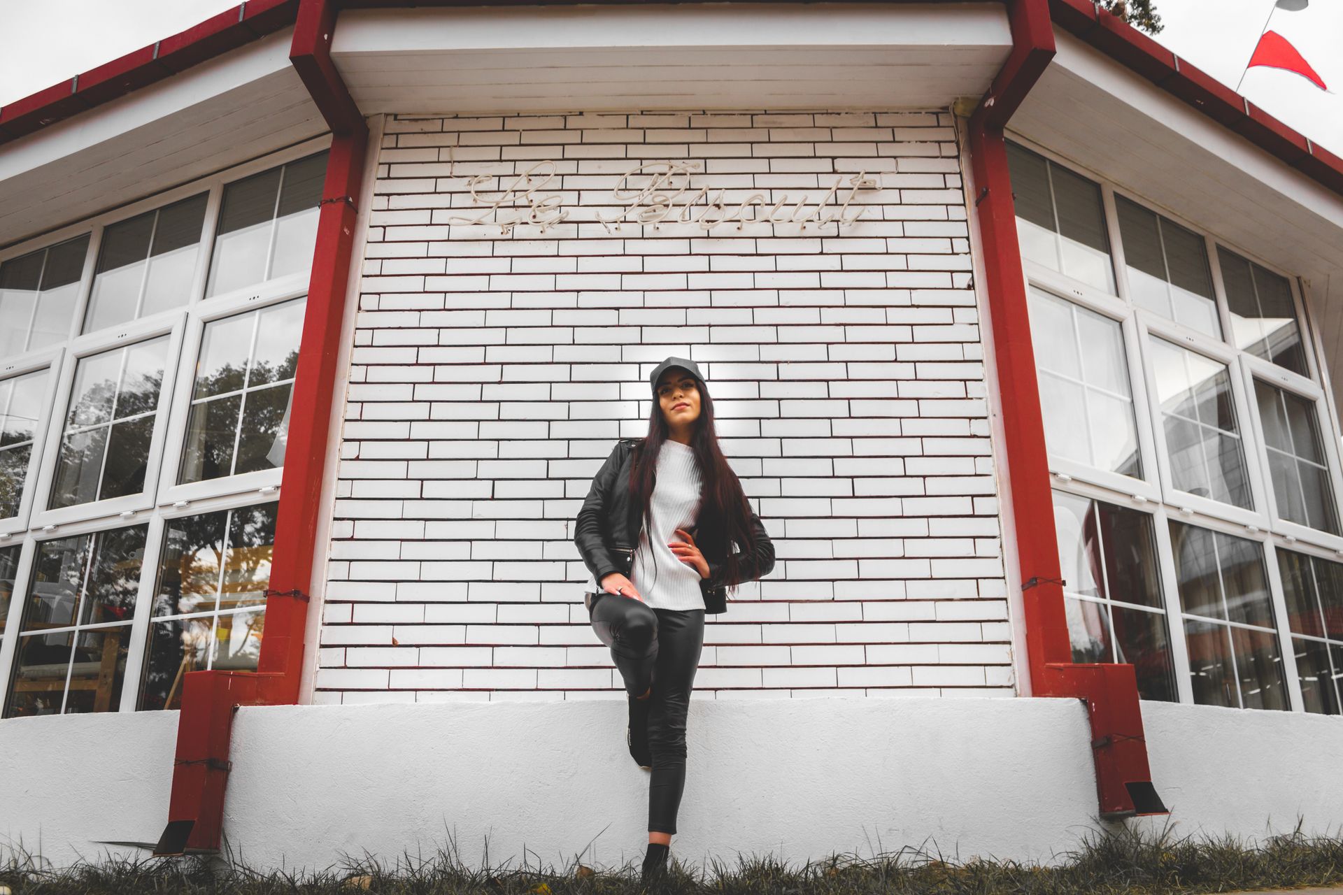Fashionable woman posing confidently in front of a modern building with glass windows.