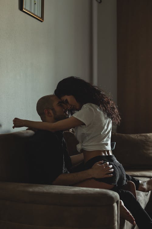 Free Woman Sitting on Her Partners Lap on a Sofa  Stock Photo