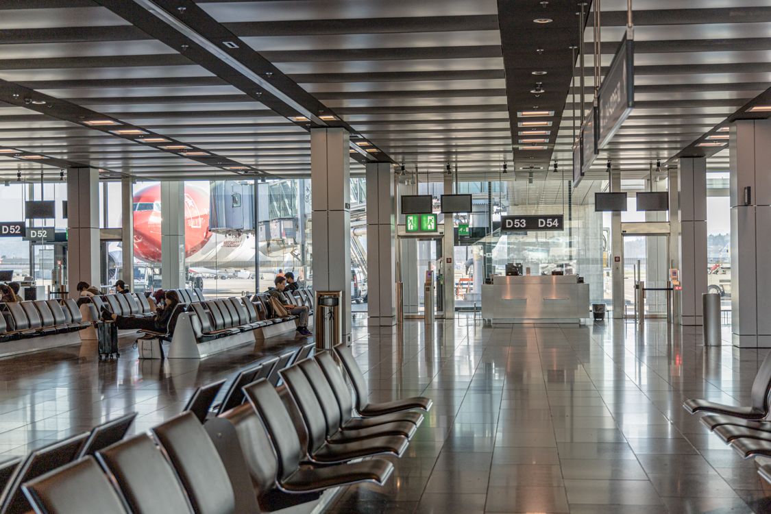 Spacious airport terminal seating area with an airplane visible through large glass windows