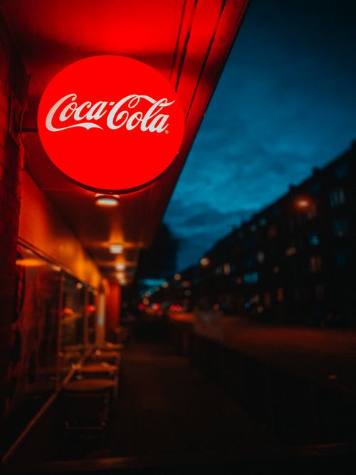 Free A glowing Coca-Cola sign adds vibrant contrast to a night street scene in Aalborg, Denmark. Stock Photo