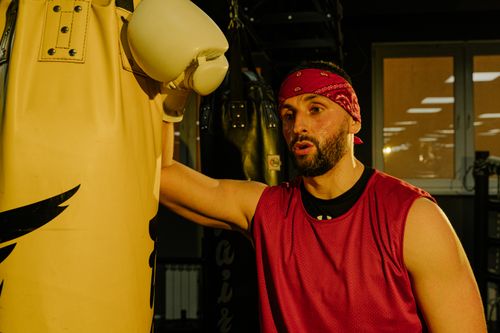 Free A boxer takes a break while training with a punching bag in a gym. Stock Photo