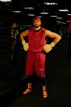 Athletic man in red sportswear posing confidently in a dimly lit gym.