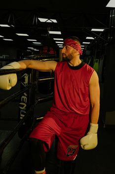 Boxer in red outfit braces for training in an indoor gym. Intense focus and preparation.