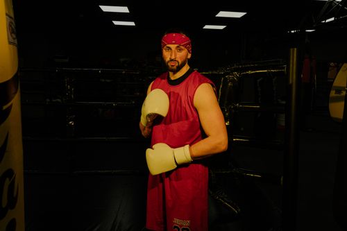 Free Male boxer in red attire posing confidently in an indoor gym. Stock Photo