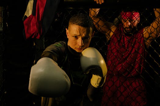 Intense boxing scene with a focused fighter and trainer in a dimly lit ring.