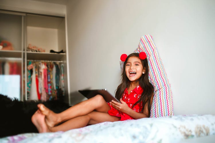 Laughing Girl Using Tablet On Bed