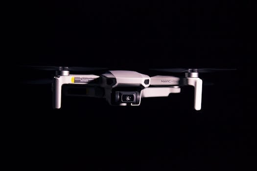 A Mavic Mini drone captured mid-flight against a dark background, showcasing modern technology in action.