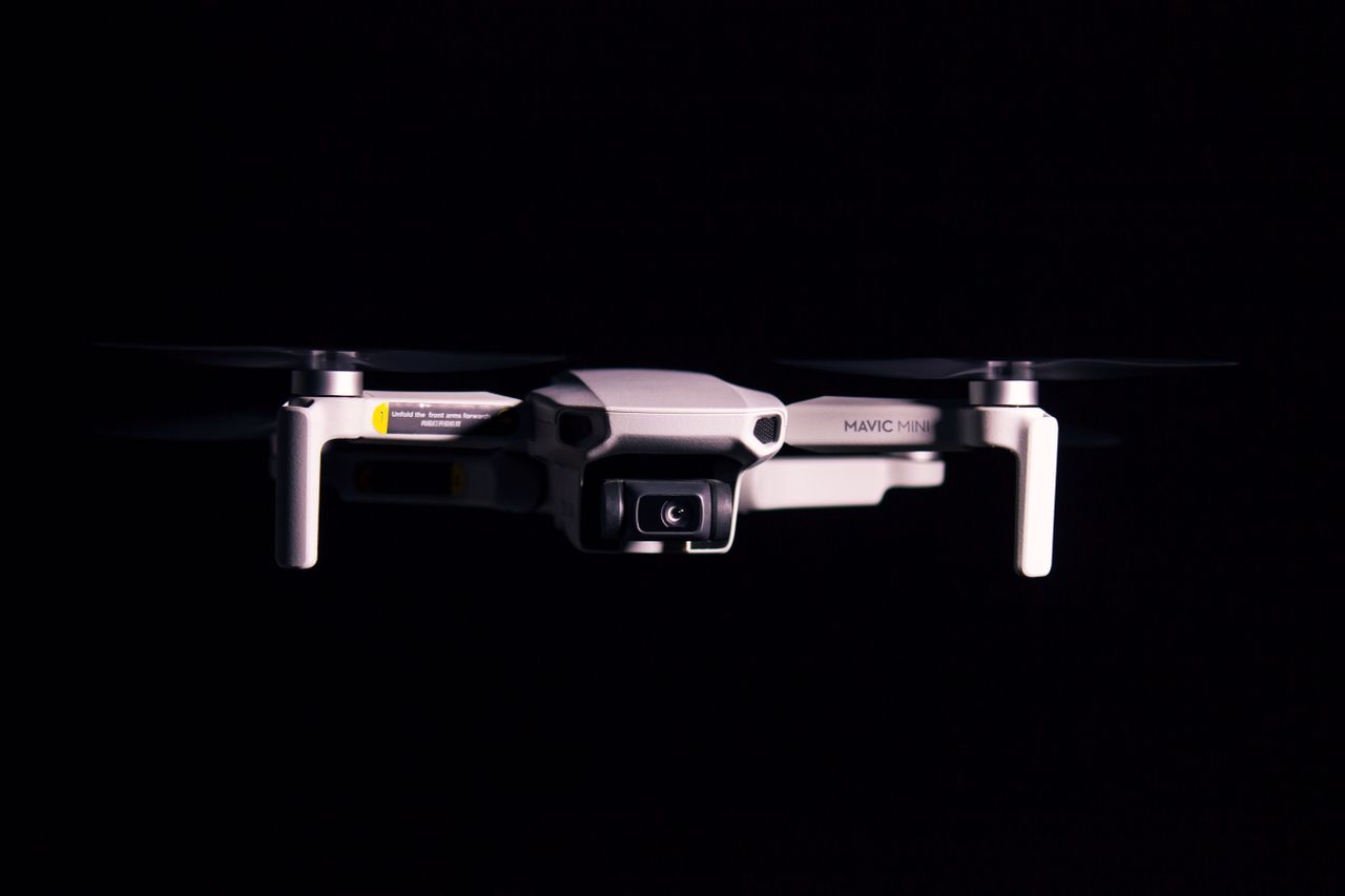 a mavic mini drone captured mid flight against a dark background showc