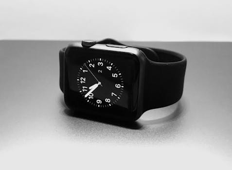 Modern black smartwatch with analog display on a neutral background.