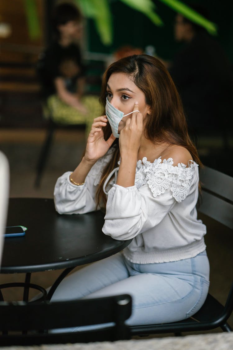 A Sitting Woman Putting On A Facemask