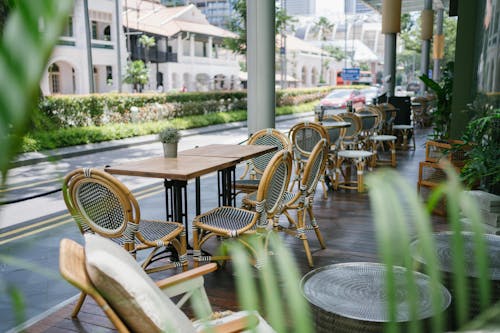 Free From above of street cafeteria interior with wooden and wicker furniture near road with bushes and contemporary houses Stock Photo