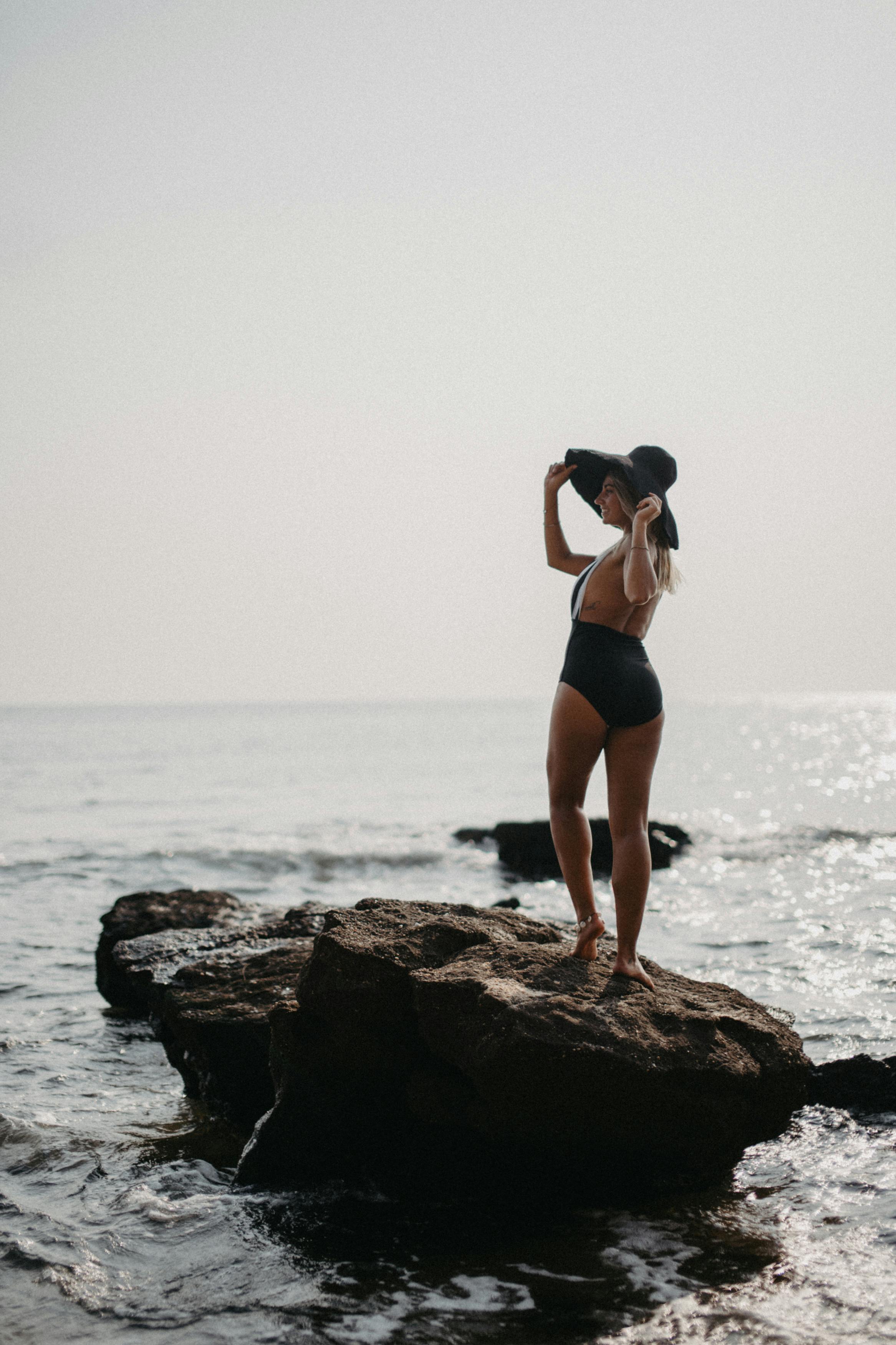 Woman in Black Bikini Standing on Rock Formation Near Sea · Free Stock