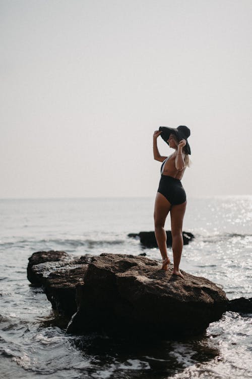 Free Woman in Black Swimsuit Standing on A Big Rock  Stock Photo