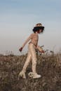 Trendy black woman walking in field in countryside