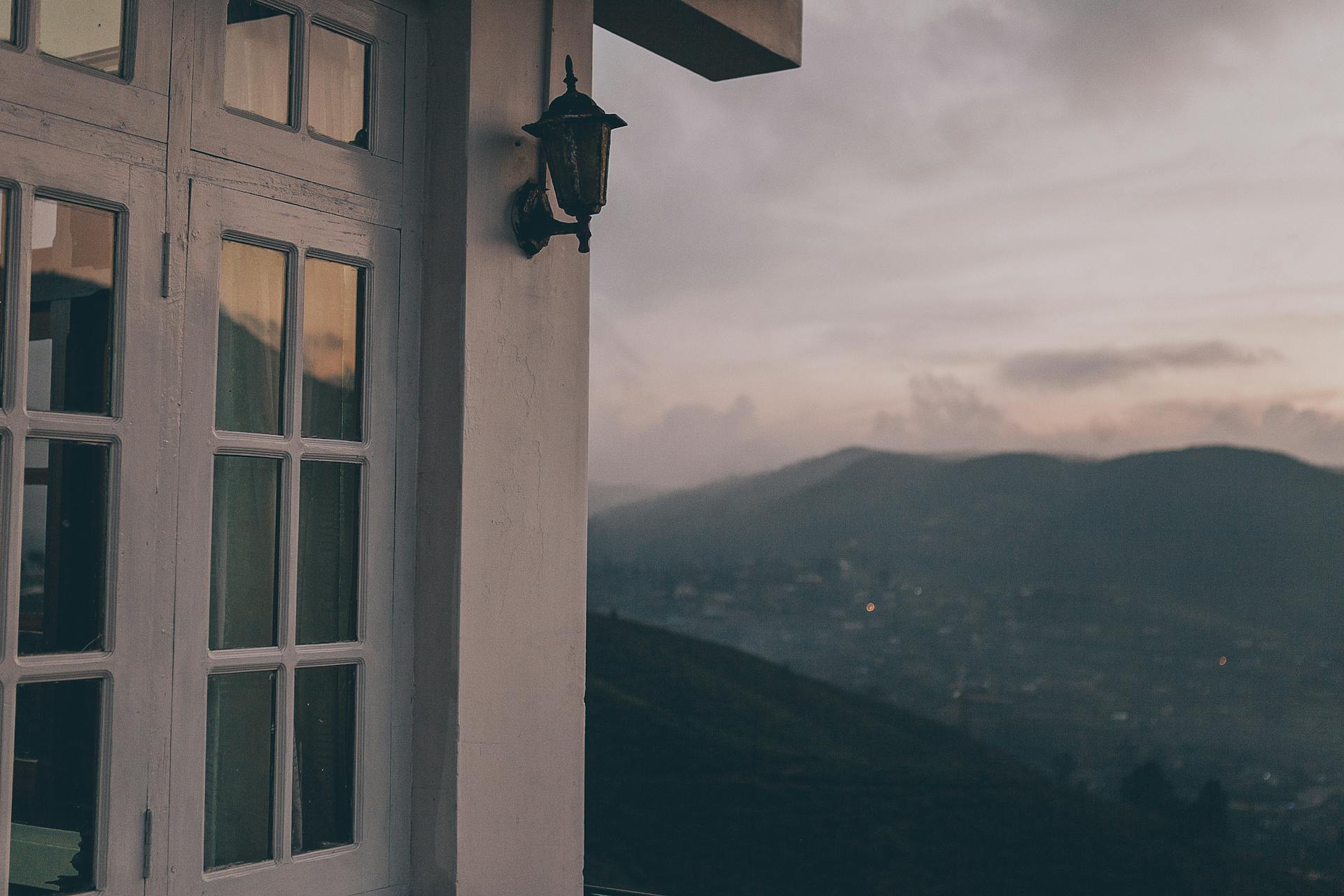 Peaceful view from a house with glass windows overlooking a misty Sri Lankan landscape at twilight.