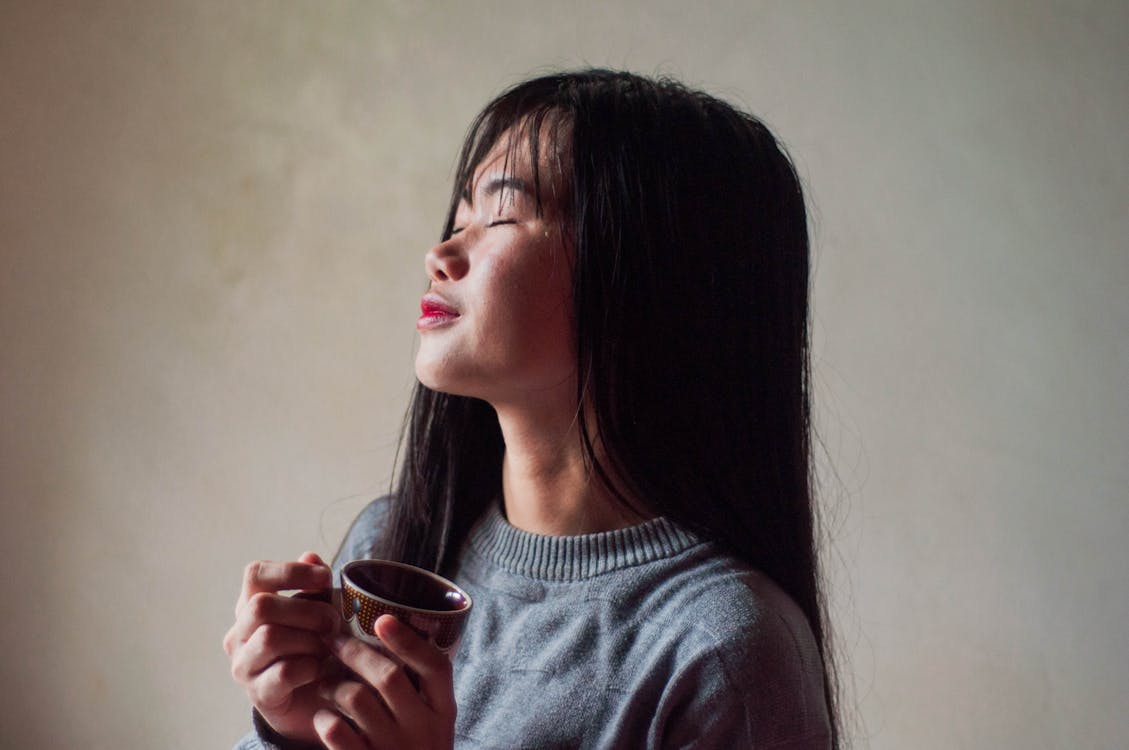 Dreamy Asian woman enjoying tea at home near wall - Want LOA Work For You