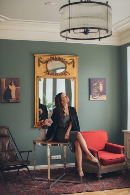 A Woman in Black Coat Sitting on a Table