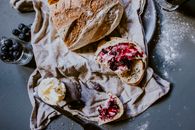 Tasty loaf of bread with blueberry confiture on table