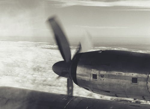 Grayscale Photo Of An Aircraft Flying Above Clouds