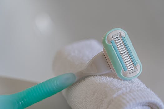 A close-up image of a disposable razor placed on a rolled white towel, suitable for hygiene and grooming themes.