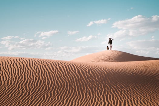 A lone traveler atop a sand dune in Al Wahat Al Dakhla Desert, Egypt.