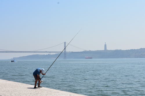 adam, Balık tutmak, deniz kıyısı içeren Ücretsiz stok fotoğraf