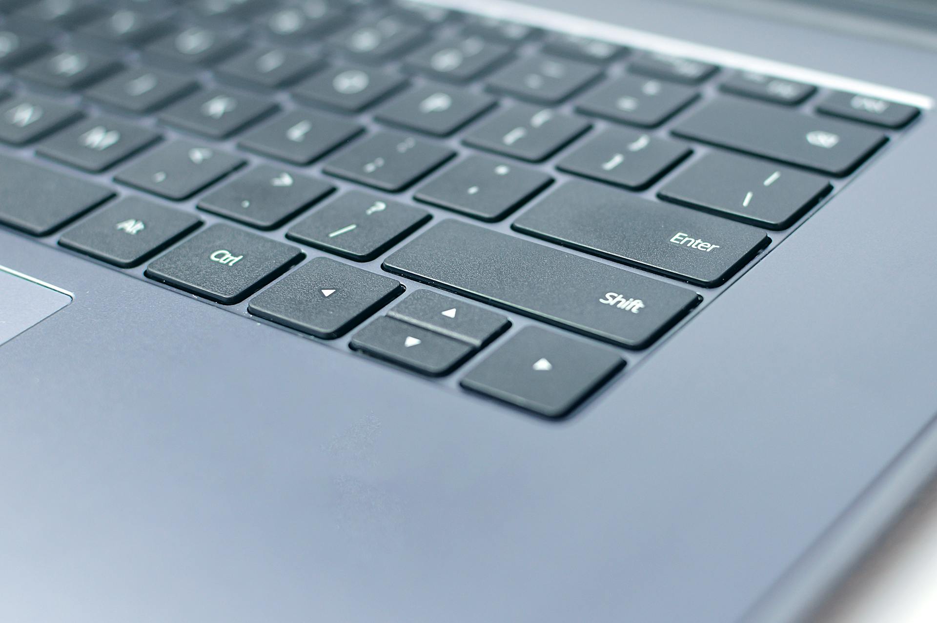 From above closeup of contemporary portable computer keyboard with words and symbols on black keys