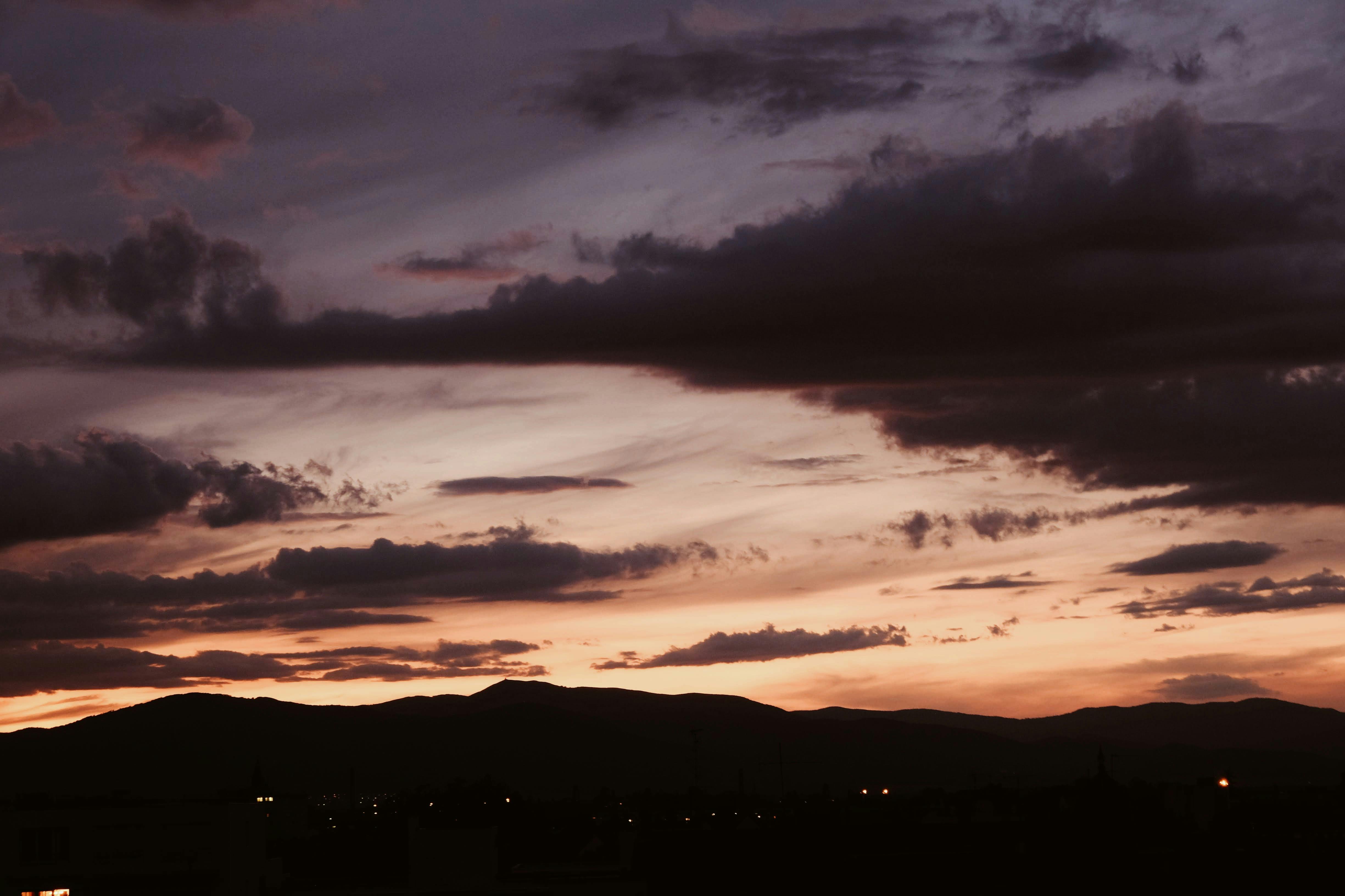 dramatic cloudy sky at sunset above mountains in twilight