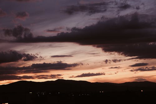 Dramatic cloudy sky at sunset above mountains in twilight