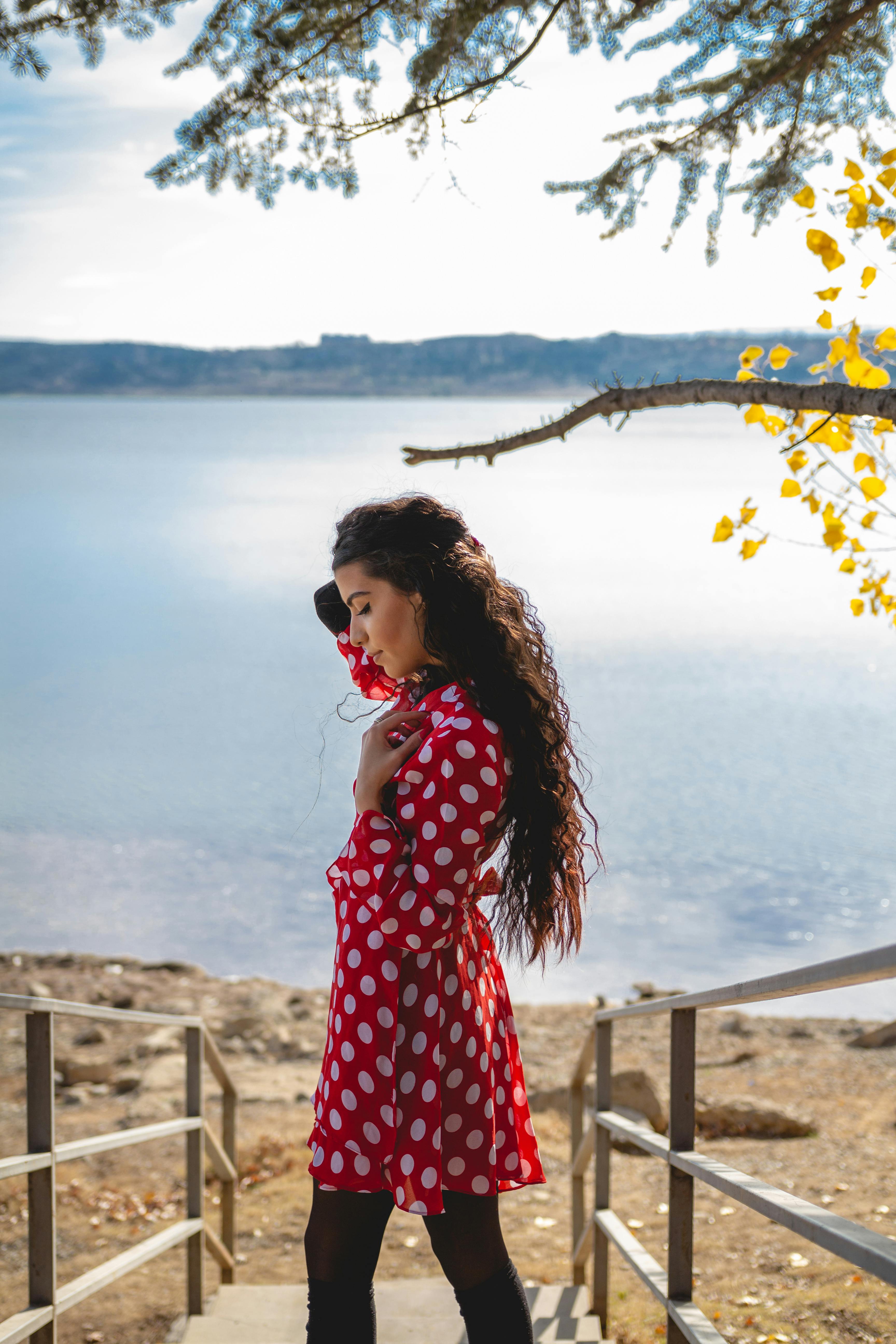 a woman in red and white polka dot dress standing near on the steps