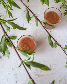 Fresh fruit smoothies on a textured surface surrounded by green branches, perfect for a healthy lifestyle vibe.