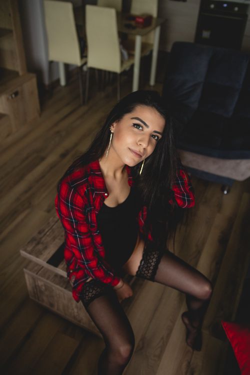Free Portrait of a woman in alluring attire sitting indoors, exuding confidence and style. Stock Photo