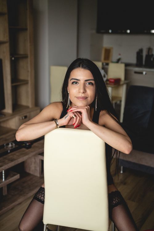 Free Portrait of a brunette woman with long hair sitting indoors, exuding elegance and style. Stock Photo